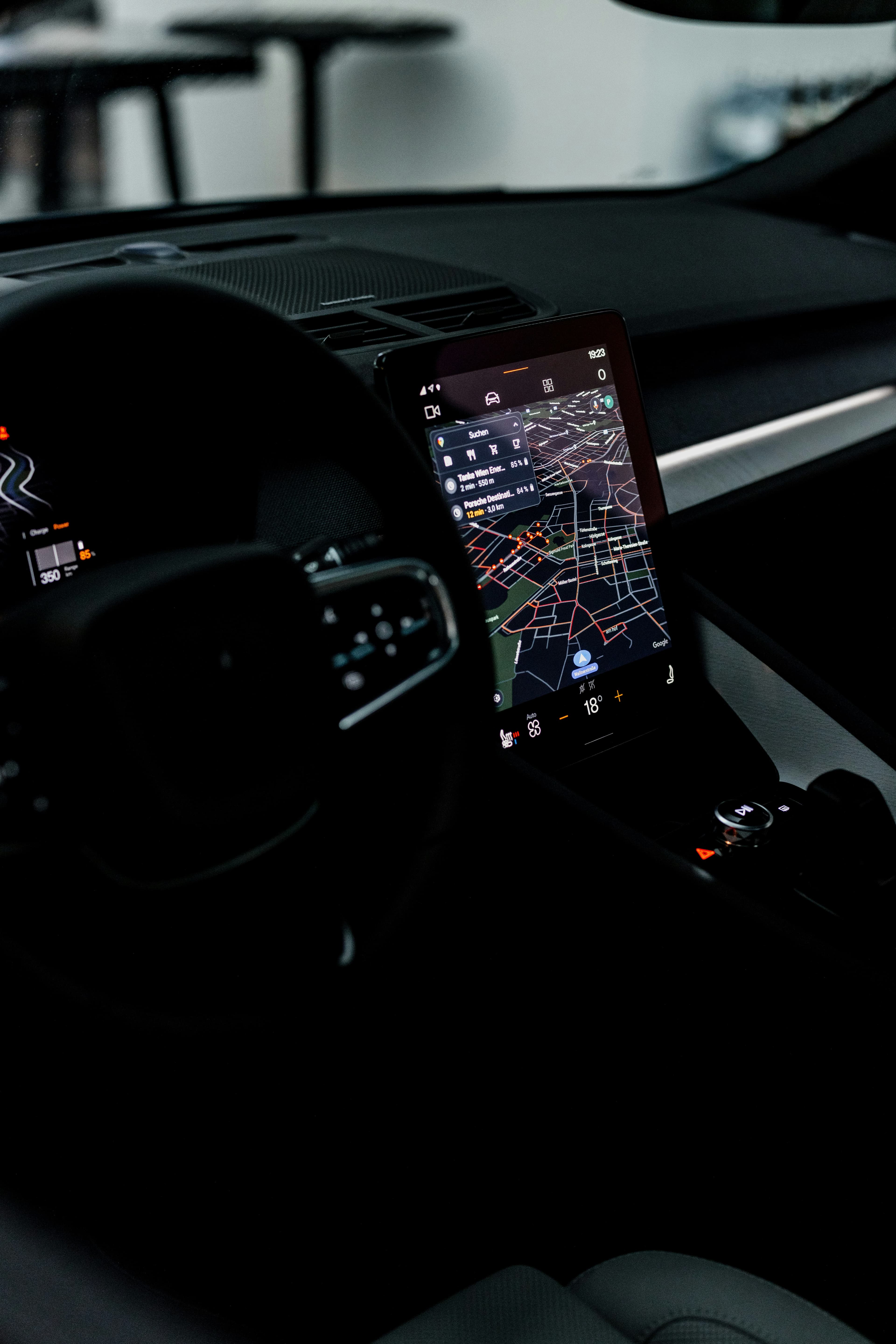 A car's dark dashboard interior with a live GPS navigation map on the center touchscreen